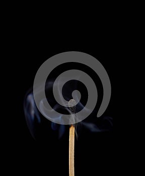 Match off on a black background with smoke