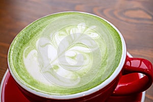 match tea latte with a latte art in red ceramic mug in a coffee shop