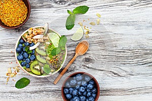 Matcha green tea breakfast superfoods smoothies bowl topped with chia, flax and pumpkin seeds, bee pollen, granola, coconut flakes