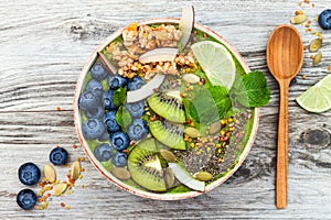 Matcha green tea breakfast superfoods smoothies bowl topped with chia, flax and pumpkin seeds, bee pollen, granola, coconut flakes