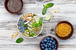 Matcha green tea breakfast superfoods smoothies bowl topped with chia, flax and pumpkin seeds, bee pollen, granola, coconut flakes