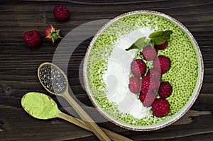 Matcha green tea chia seed pudding bowl, vegan dessert with raspberry and coconut milk. Overhead, top view, flat lay.