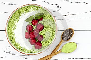 Matcha green tea chia seed pudding bowl, vegan dessert with raspberry and coconut milk. Overhead, top view, flat lay.