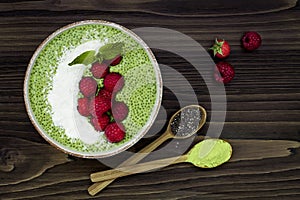 Matcha green tea chia seed pudding bowl, vegan dessert with raspberry and coconut milk. Overhead, top view, flat lay.