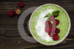 Matcha green tea chia seed pudding bowl, vegan dessert with raspberry and coconut milk. Overhead, top view, flat lay.