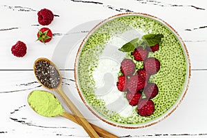 Matcha green tea chia seed pudding bowl, vegan dessert with raspberry and coconut milk. Overhead, top view, flat lay.