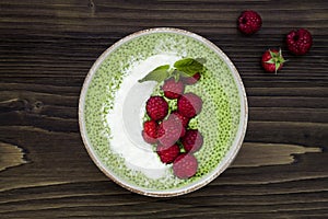 Matcha green tea chia seed pudding bowl, vegan dessert with raspberry and coconut milk. Overhead, top view, flat lay.