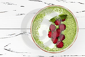 Matcha green tea chia seed pudding bowl, vegan dessert with raspberry and coconut milk. Overhead, top view, flat lay.