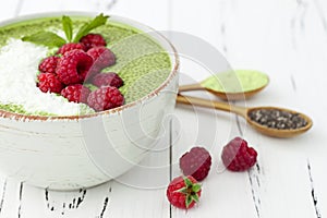 Matcha green tea chia seed pudding bowl, vegan dessert with raspberry and coconut milk. Overhead, top view, flat lay.