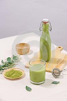 Matcha green tea latte in bottle and cup glass on white background