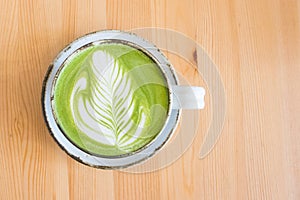 Matcha green tea latte in a cup on wooden table background.Hot Matcha coffee latte with beautiful milk foam latte art texture