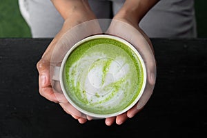 Matcha green tea latte in woman hand,top view