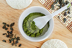 Matcha green tea powder in a white bowl, close up. Natural beauty treatment and spa. Homemade matcha mask recipe.