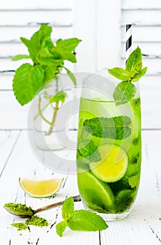 Matcha iced green tea with lime and fresh mint on white rustic background. Super food drink.