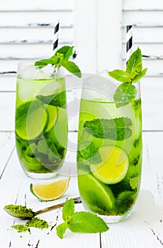 Matcha iced green tea with lime and fresh mint on white rustic background. Super food drink.