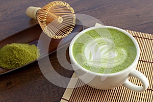 Matcha latte art heart shape on top on wooden table with some gr