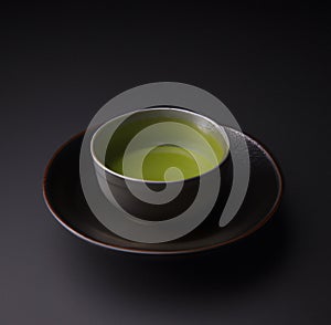 Matcha tea in the cup isolated on black background. Japanese tea ceremony concept.