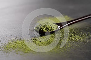 Matcha and wooden spoon on black background