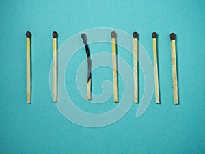 Matches on a blue background. One against all. Burnt match