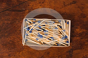 Matches with the part of the match or with the blue head, in their cardboard box, grouped on a wooden table.