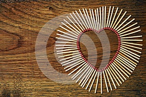 Matches on a wooden background form abstract heart. Copy space for text. Passionate hot love concept