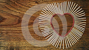 Matches on a wooden background form abstract heart. Copy space for text. Passionate hot love concept