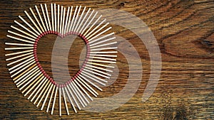 Matches on a wooden background form abstract heart. Copy space for text. Passionate hot love concept