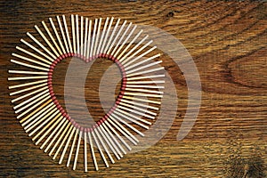 Matches on a wooden background form abstract heart. Copy space for text. Passionate hot love concept