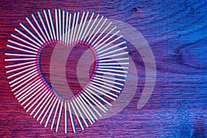 Matches on a wooden background form abstract heart. Neon light. Copy space for text. Passionate hot love concept