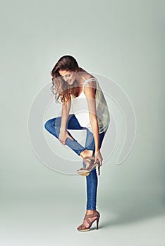 Matching the perfect pair of shoes to complete her look. Studio shot of a beautiful young woman getting undressed