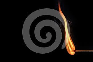 Matchstick with a big flame on a black background with free space for text