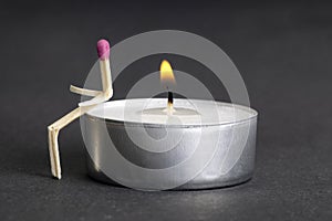 Matchstick character sitting on a lit tea candle. Loneliness and unrequited love concept