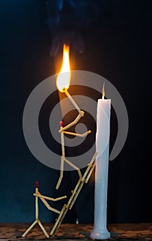 Matchsticks in form of a man lighting a candle, matchstick man lighting a candle.