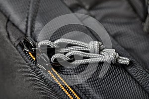 The material of the textile accessories is black. Metal zipper closure with gray strings close-up on blurred background