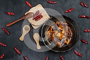 Material of traditional chinese food,spicy Mapo Tofu decorates with chilis and hot peppers on black background