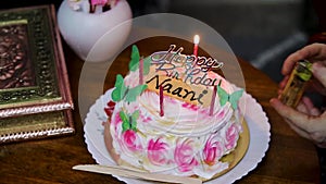 maternal grandmother lighting maternal grandmother candles with birthday cake at coffee table