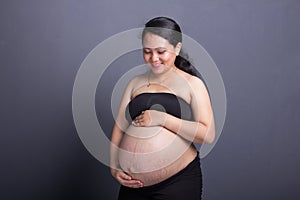 During maternity childbearing woman in black clothes caresses her belly