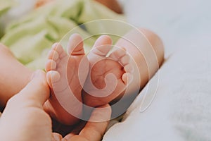 Maternity concept. Mom`s hand touching cute little newborn baby feet.