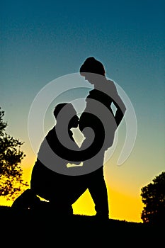 Maternity couple silhouette man kissing pregnant belly of pregnant wife