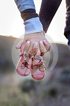 Maternity photo shoot, a father and pregnant mother holding new babies shoes