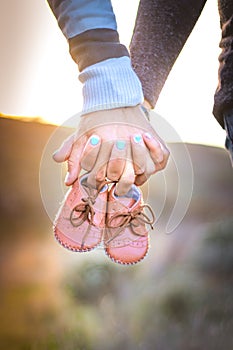 Maternity photo shoot, a father and pregnant mother holding new babies shoes