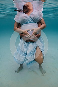 Maternity shoot underwater with young pregnant lady.