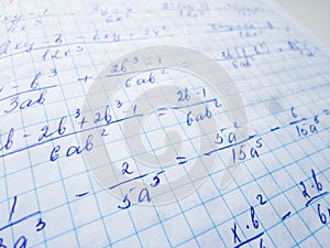 Math formulas are written in a notebook with a pen. The solution of examples and problems in a notebook
