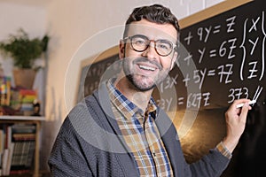 Math teacher writing with chalk in classroom