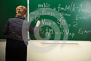 Math teacher writing formula on the blackboard