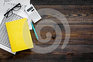 Math textbook or tutorial near sheet with numbers, countes and calculator ondark wooden background top view copy space