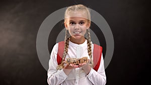 Math word on wooden cubes in cute schoolgirl hands, educational system, lesson