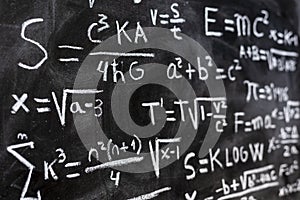 Mathematical equations and physics formulas handwritten on blackboard