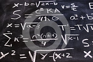 Mathematical equations and physics formulas handwritten on blackboard