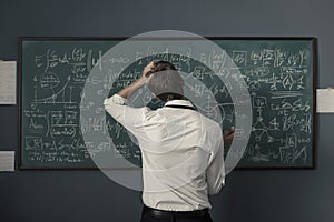 Mathematician solving problems and writing formulas on the chalkboard